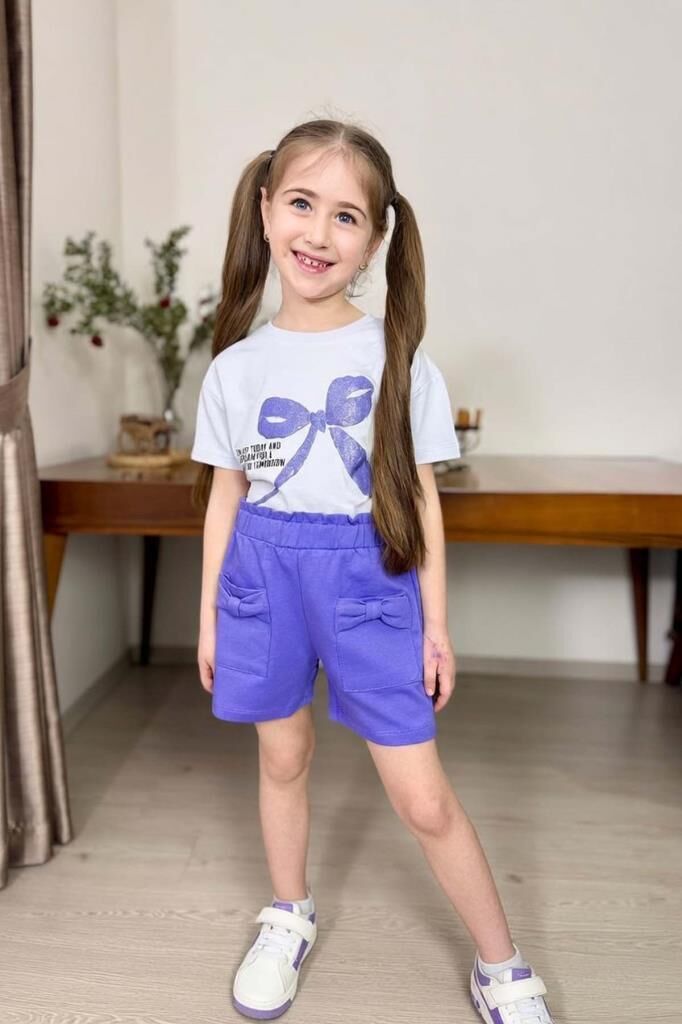 Kız Çocuk Üzerinde Digital Kurdela Basklı T-Shirt ve Fiyonk Cep Detaylı Lila Şortlu Takım