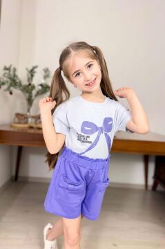 Kız Çocuk Üzerinde Digital Kurdela Basklı T-Shirt ve Fiyonk Cep Detaylı Lila Şortlu Takım